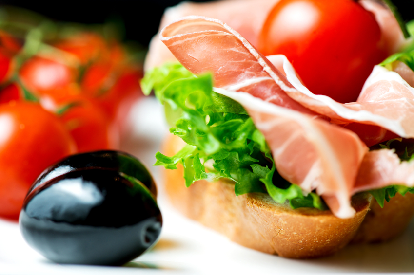 Sandwiches with prosciutto on plate with olive horizontal