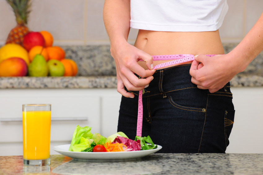 woman eating salad and fruits and measuring her waist