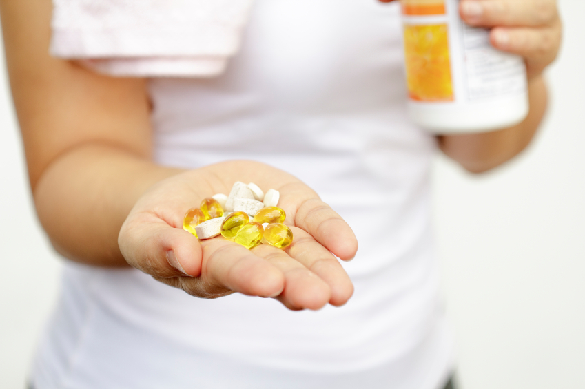 sport and diet concept - woman hand with vitamins and medication