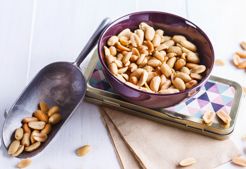 Roasted peanuts on a bowl over white wooden background