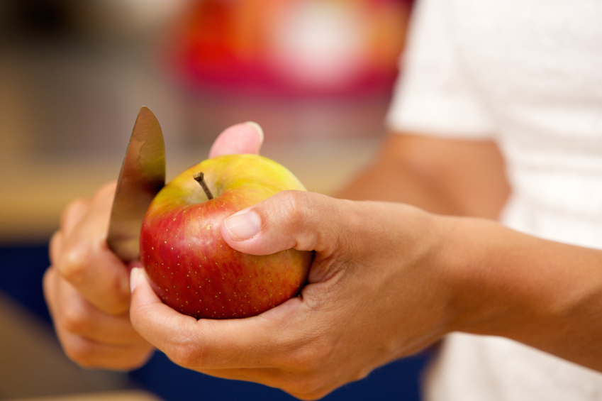 Female hands slicing apple with knife