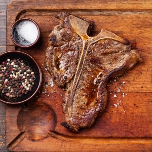 Grilled T-Bone Steak with salt and pepper  on meat cutting board fiorentina