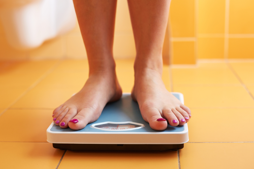 A pair of female feet standing on a bathroom scale