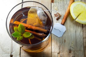 healthy cup of hot tea on wooden background, lemon and cinnamon