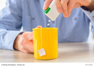 Sweetener tablets and hand with box whit cup of tea