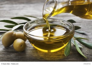 Bottle pouring virgin olive oil in a bowl close up